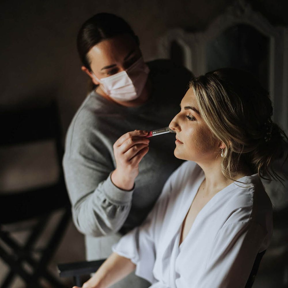 Bride in a white robe gets her makeup done for her wedding day 