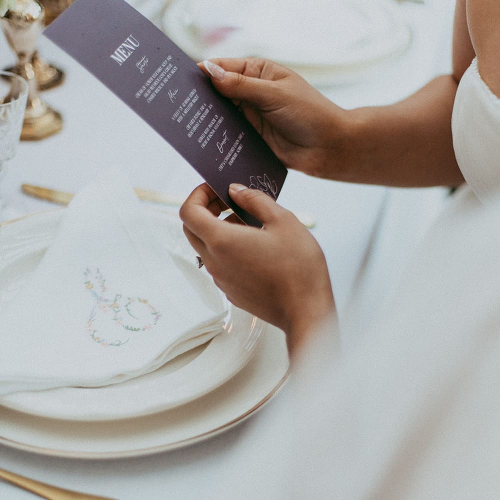 Bride reading lavender wedding menu at minimalistic wedding tablescape 