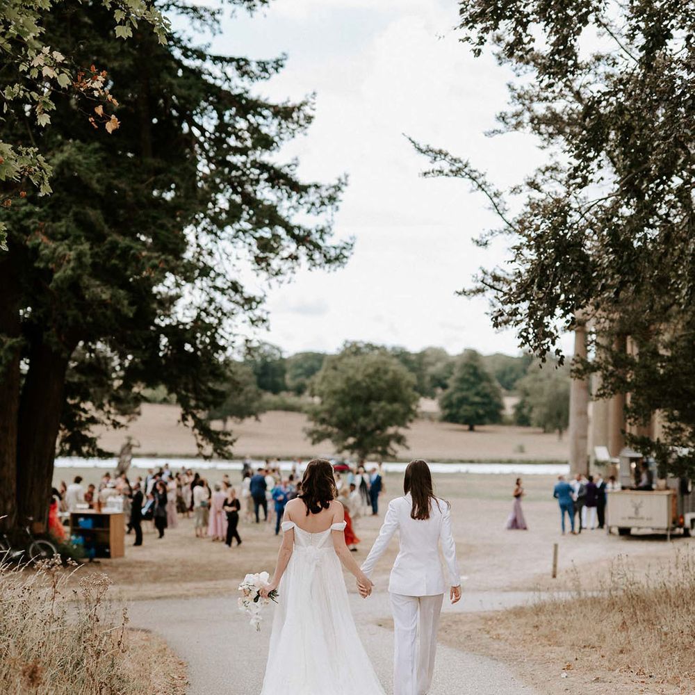 The brides walk hand in hand to their guests enjoying the summer weather outside at the Wilderness Reserve 