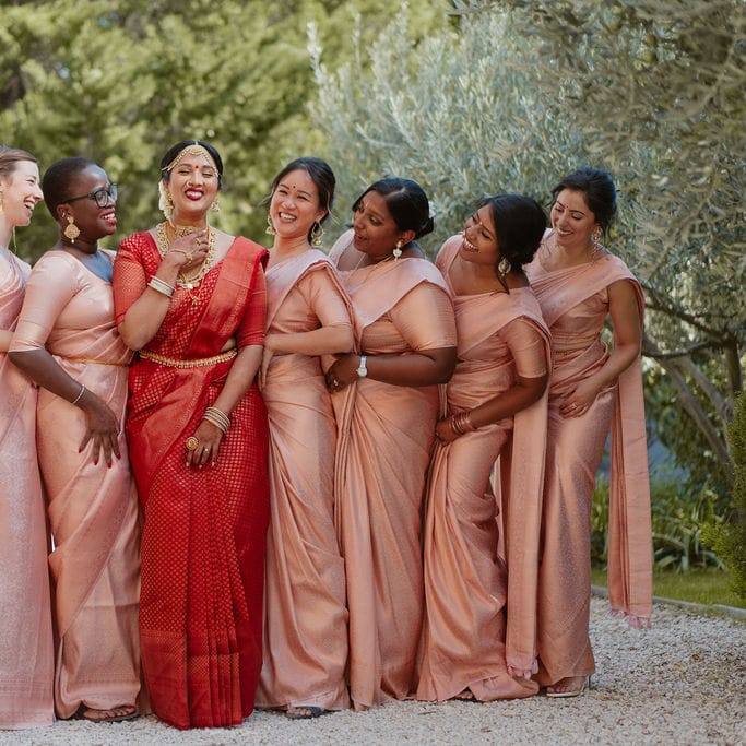 Bridal party with bride in a red lehenga and pink bridesmaids dresses