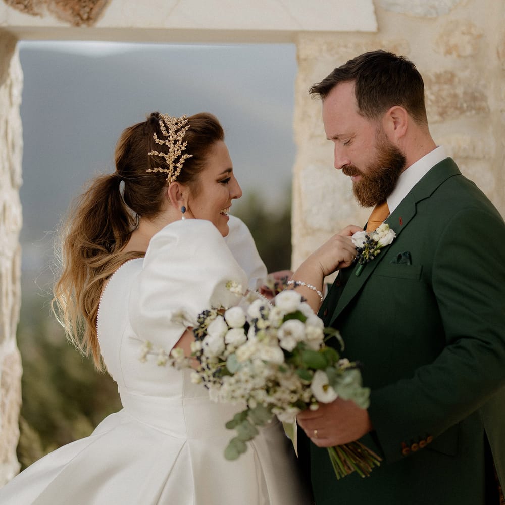 Bride in white satin dress and gold leaf bridal crown with groom in dark green groom suit at private villa wedding in Greece