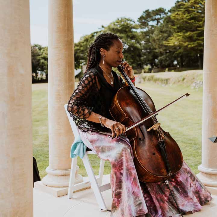 Live wedding Cellist entertainment wearing black fishnet jumper and pink and purple tie dye skirt 
