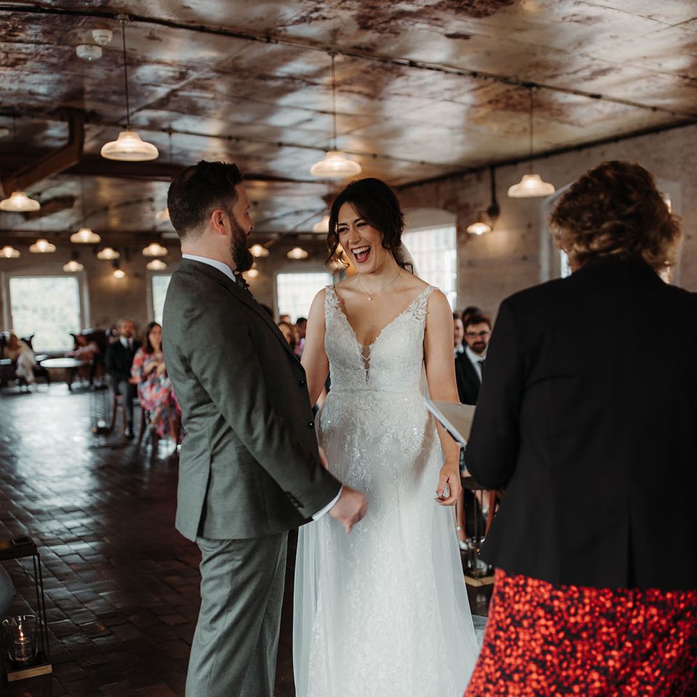 Bride in floral lace wedding dress with the groom in a green suit for their autumnal wedding 