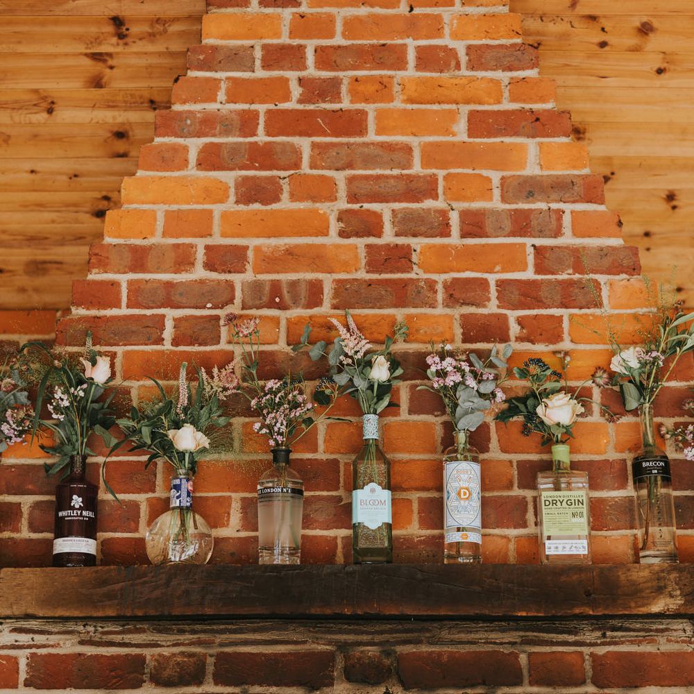 Gin bottles filled florals line brick wall