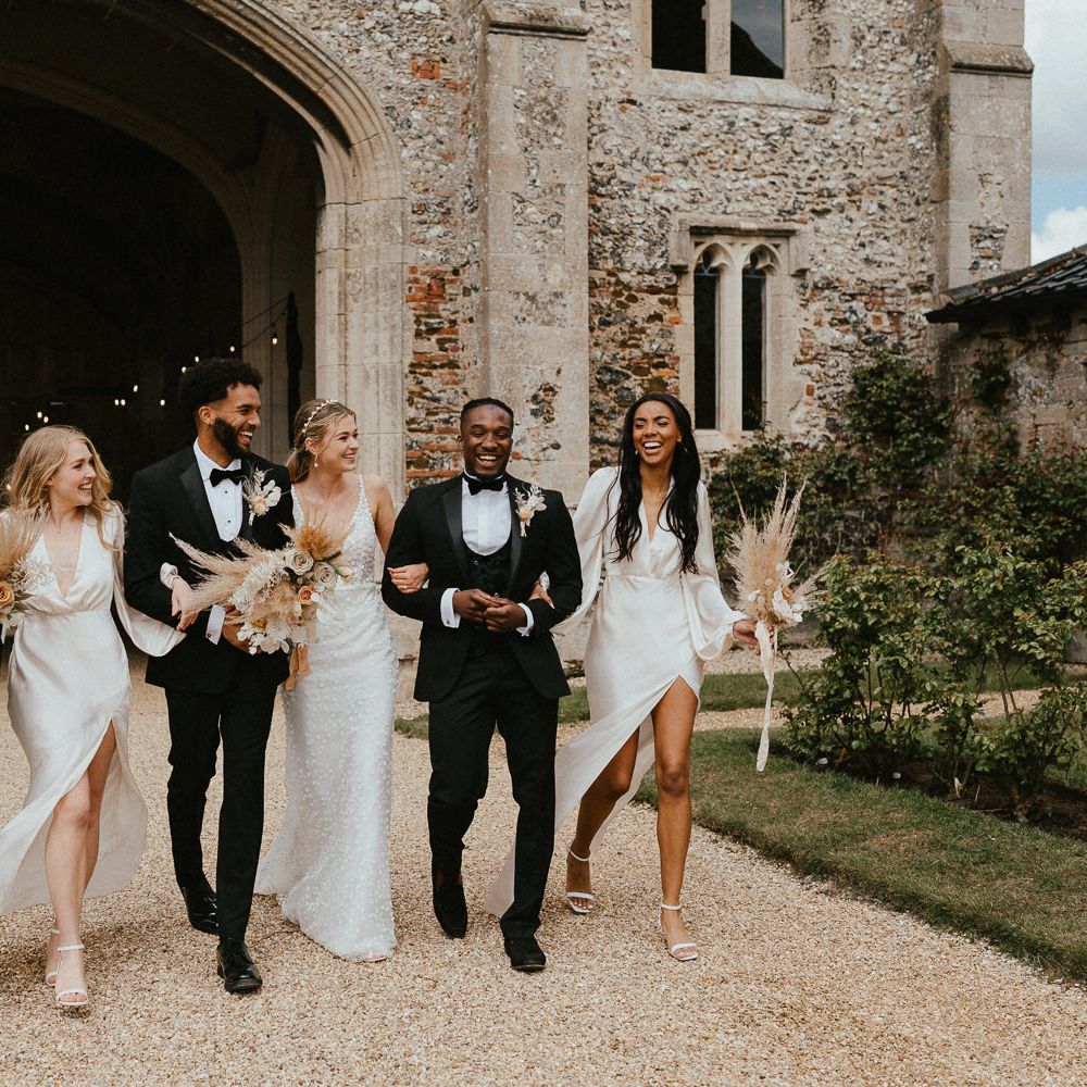 Stylish wedding party picture with groomsmen in tuxedos, bridesmaids in champagne satin dresses and the bride and appliqué gown 