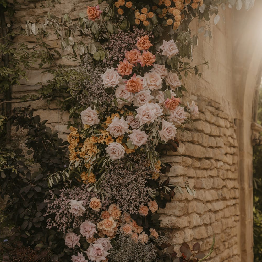 Pastel orange, coral, pink, and peach wedding flowers decorating the castle arch at Euridge Manor 