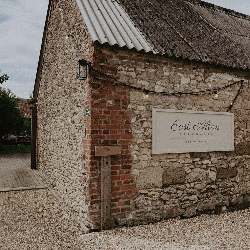 Sign on side of stone barn reading 'East Afton Farmhouse Isle of Wight' 