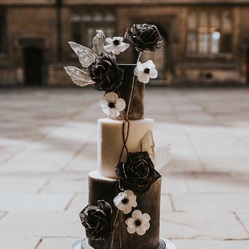 Black and white three tier wedding cake with Anemone and rose wedding flower decoration 