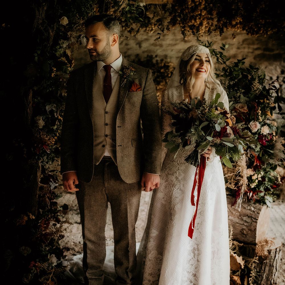 Bride in a lace wedding dress and Juliet cap veil holding hands with her groom in a wool suit at the altar of their Lyde Court wedding