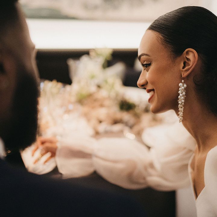 Black bride with central parting wedding hairstyle and pony tail wearing dangly pearl earrings 
