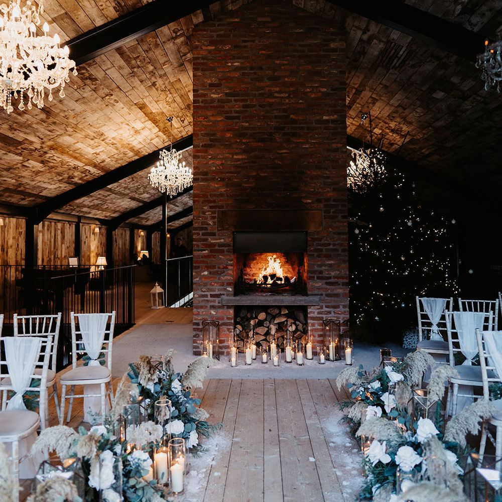 Cosy open fireplace with Christmas tree, chandeliers, dried flower decorations and candle lanterns fir wedding ceremony 