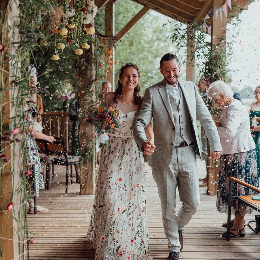 Bride and groom walk through confetti at their botanical outdoor wedding 
