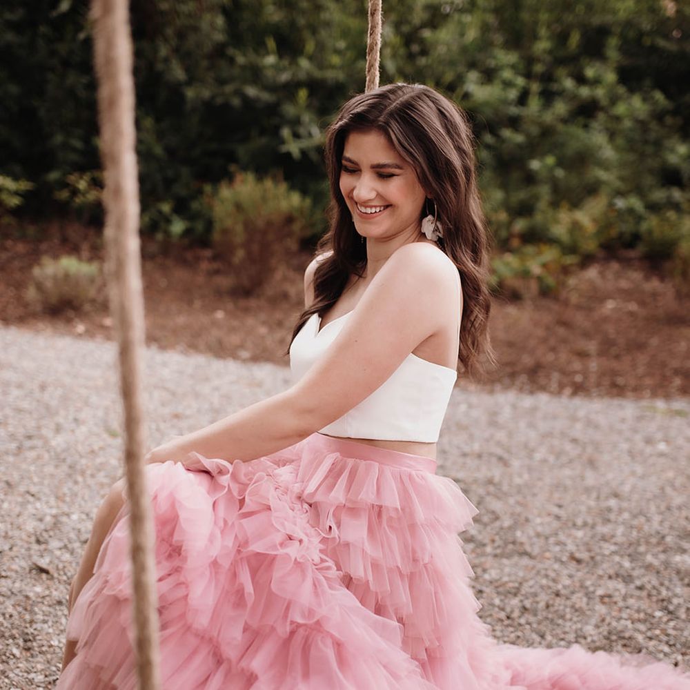 Bride in a layered pink skirt and white crop top sitting on a swing at Ballykealey House