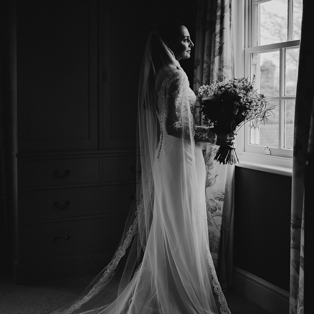 Bride in classic satin wedding dress with sheer lace sleeves and lace embroidered edge veil for traditional wedding