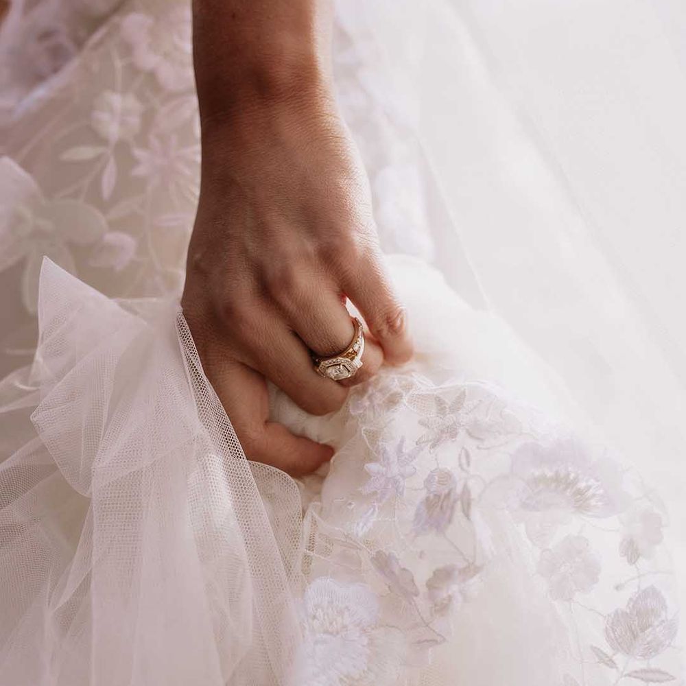 Bride in floral applique Wedding dress with gold and diamond engagement ring 