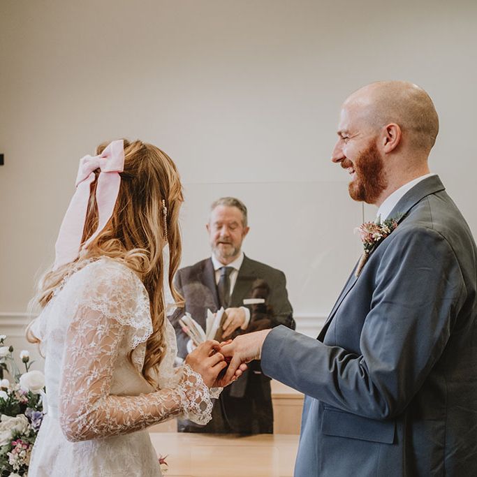 Bride places wedding ring on her grooms finger during intimate civil ceremony at St. George's Hall, Liverpool 