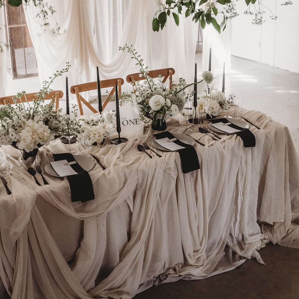 Black and white table setting with wedding drapes, black taper candles, white flowers at Willow Grange Farm