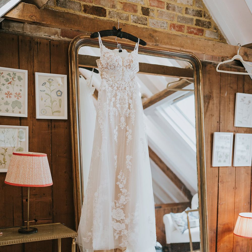 Floral lace wedding dress hanging up for the bride on her wedding day 