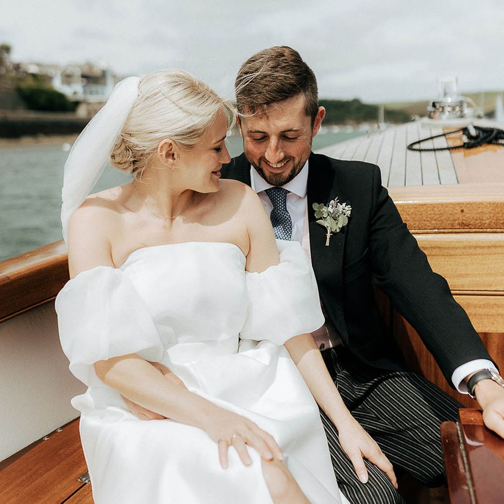 Bride & groom sit with one another during boat ride for Salcombe wedding 