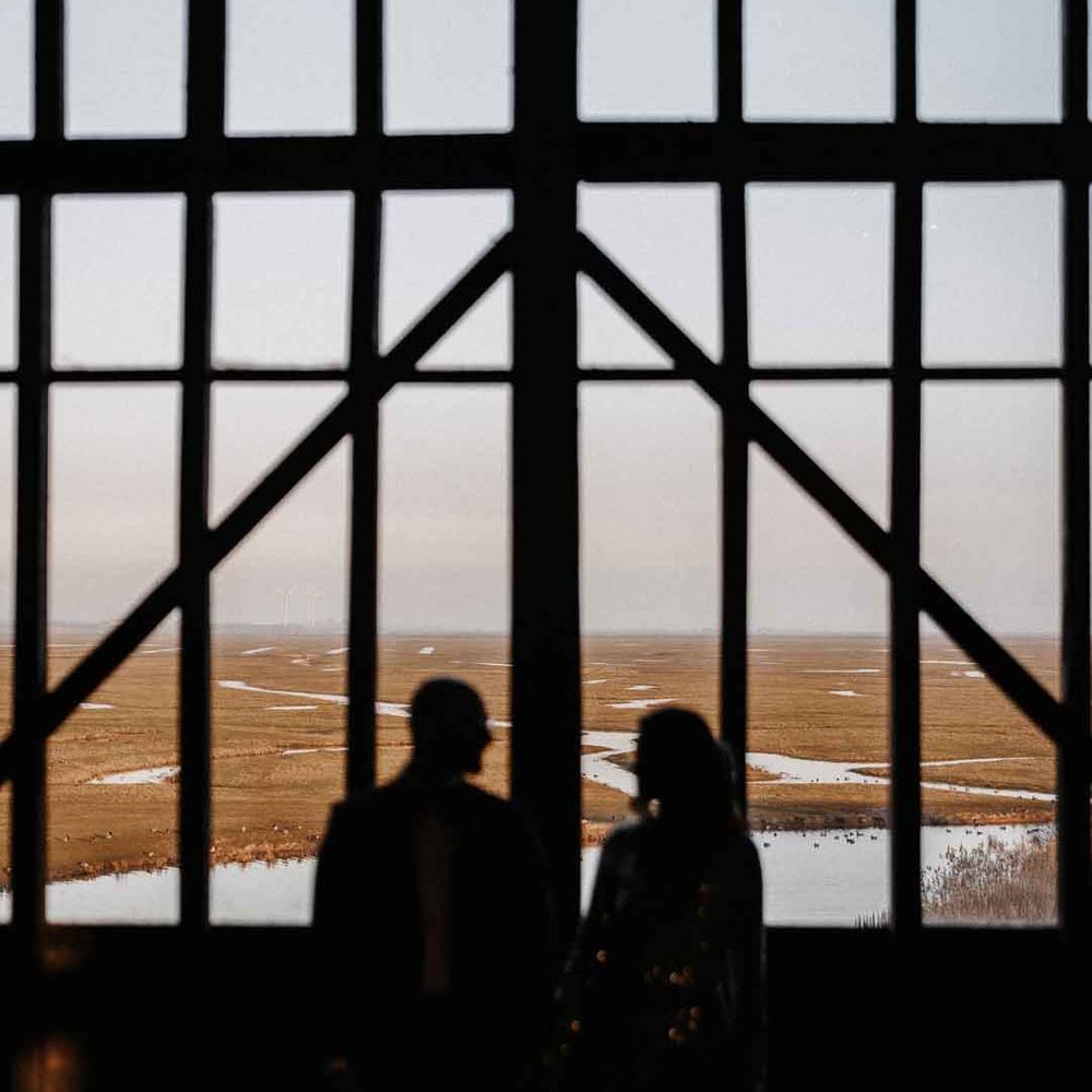 Bride and groom looking out at Elmley Nature Reserve wedding venue - Kent wedding venues 
