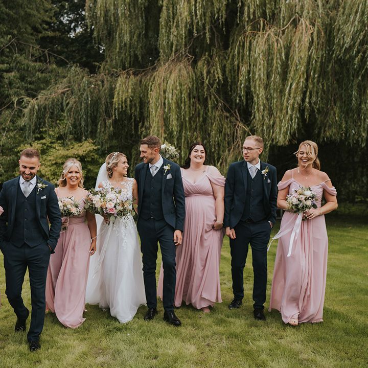 The wedding party for the Dove Barn Wedding with the bridesmaids in pink matching bridesmaid dresses and the groomsmen in navy suits 