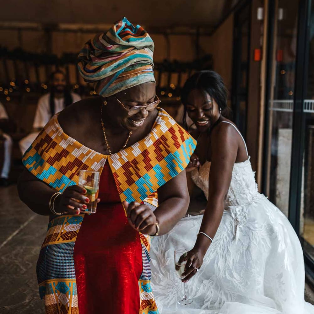 Bride in sweetheart neckline lace wedding dress and wedding guest in traditional Ghanaian wedding outfit at Lains Barn wedding