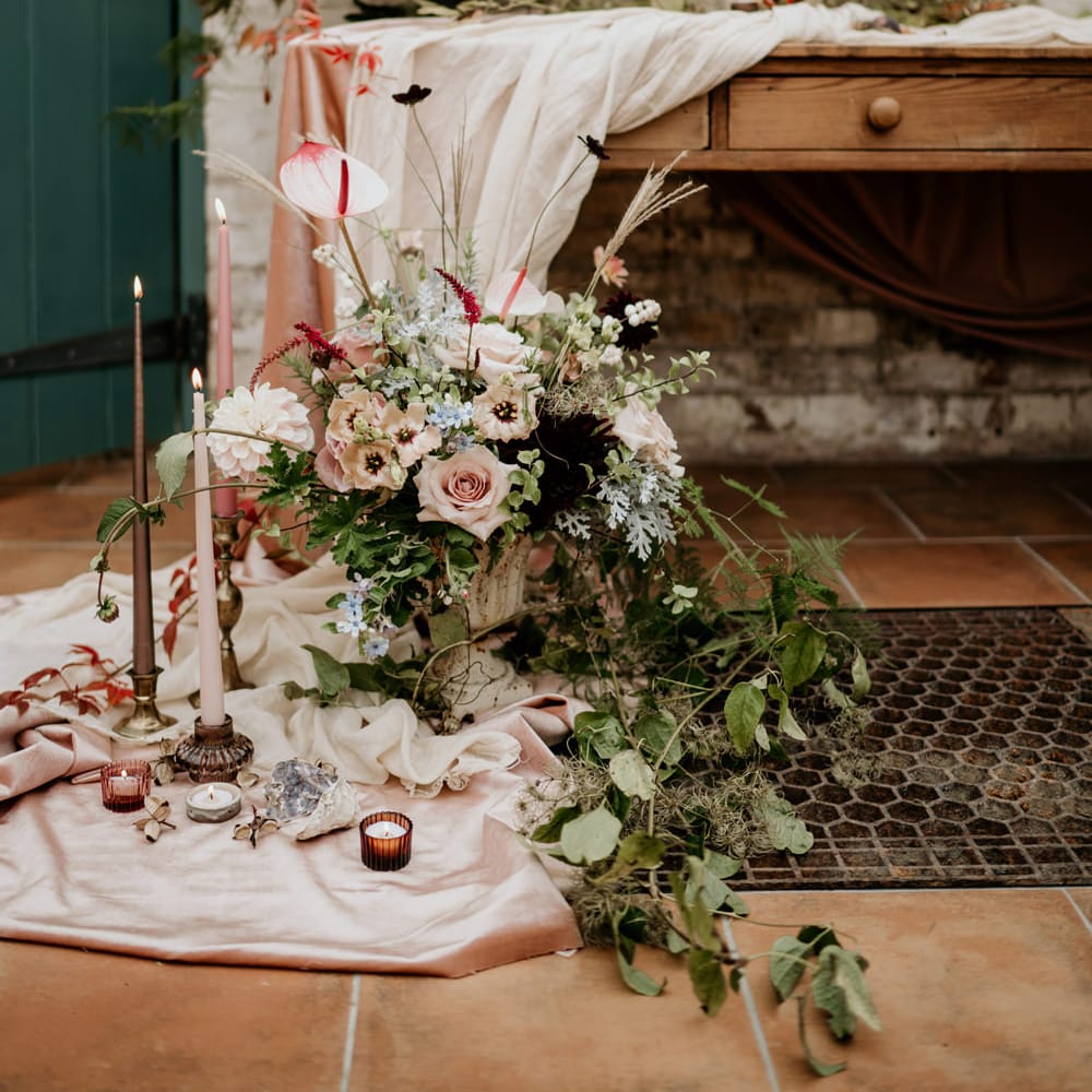 Natural linens and wedding flowers draped over the tablescape with pink anthuriums, roses and dahlias 
