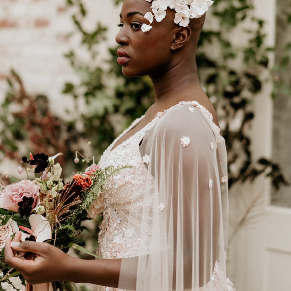Black bride with alopecia in a floral headdress and bridal cape 