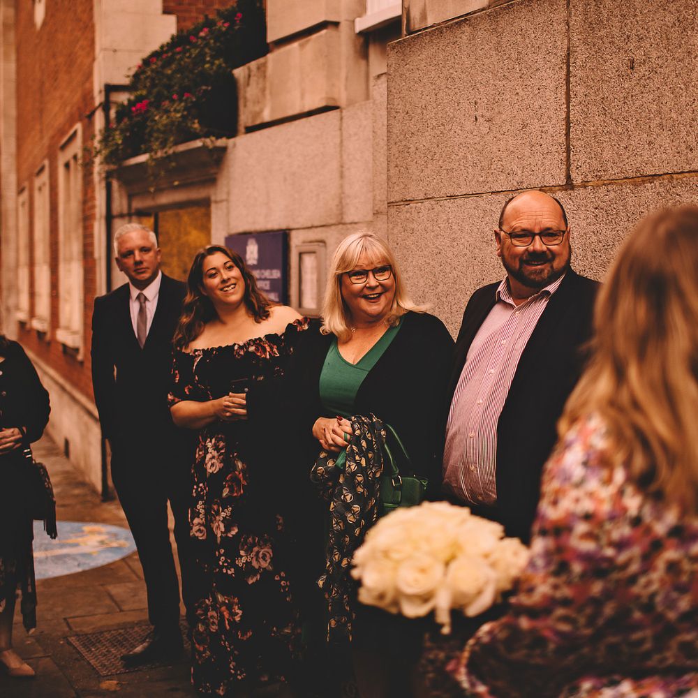 Bride & groom stand outdoors with wedding party after marrying 