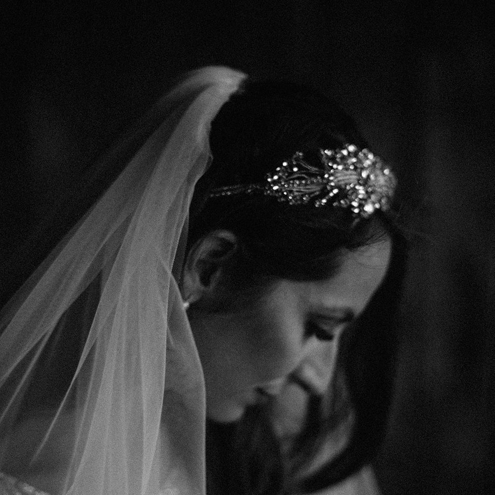 Black & white image of bride as her veil frames face and she looks down