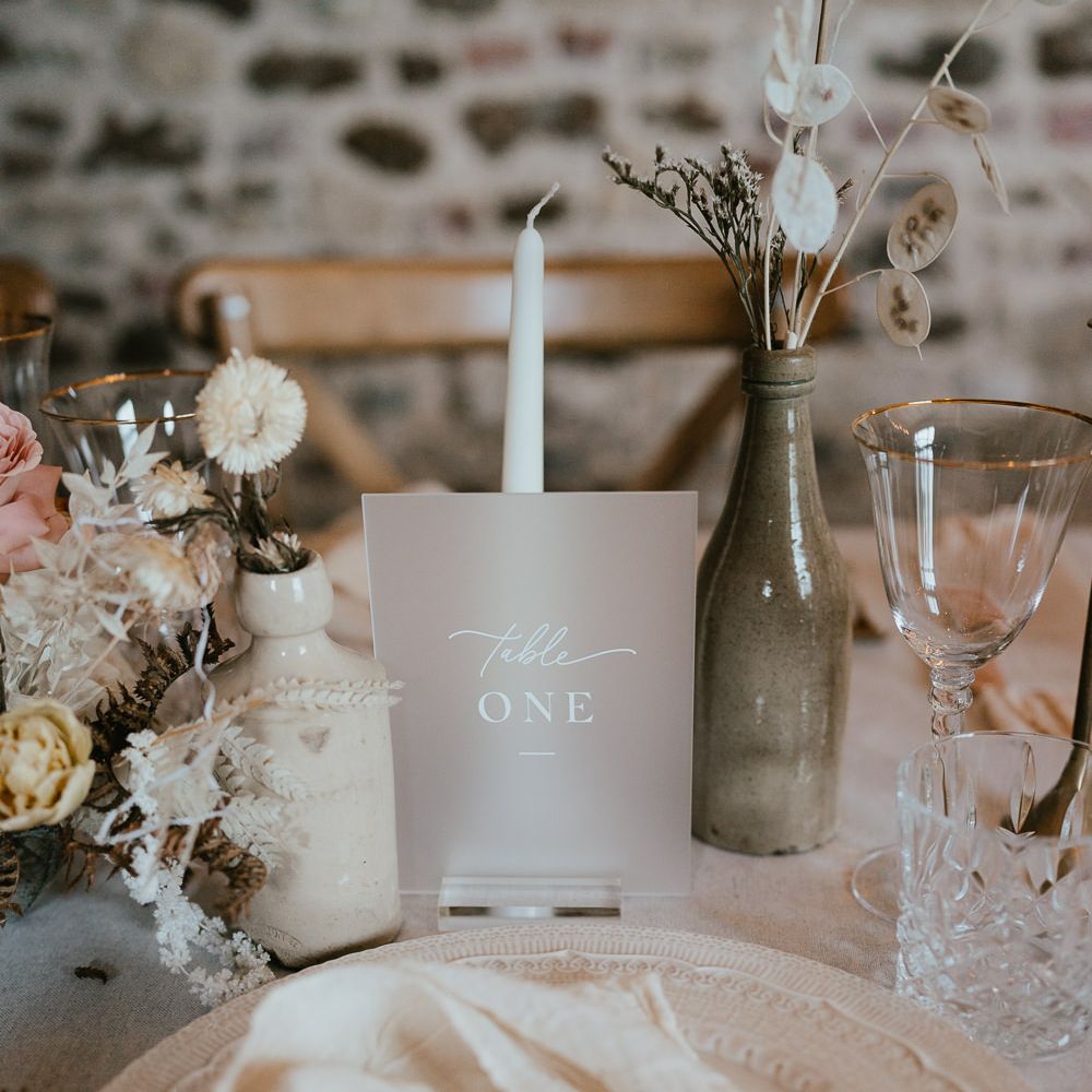 Vellum table sign with white font. Plus, white taper candles and dried flower arrangements in neutral tones 