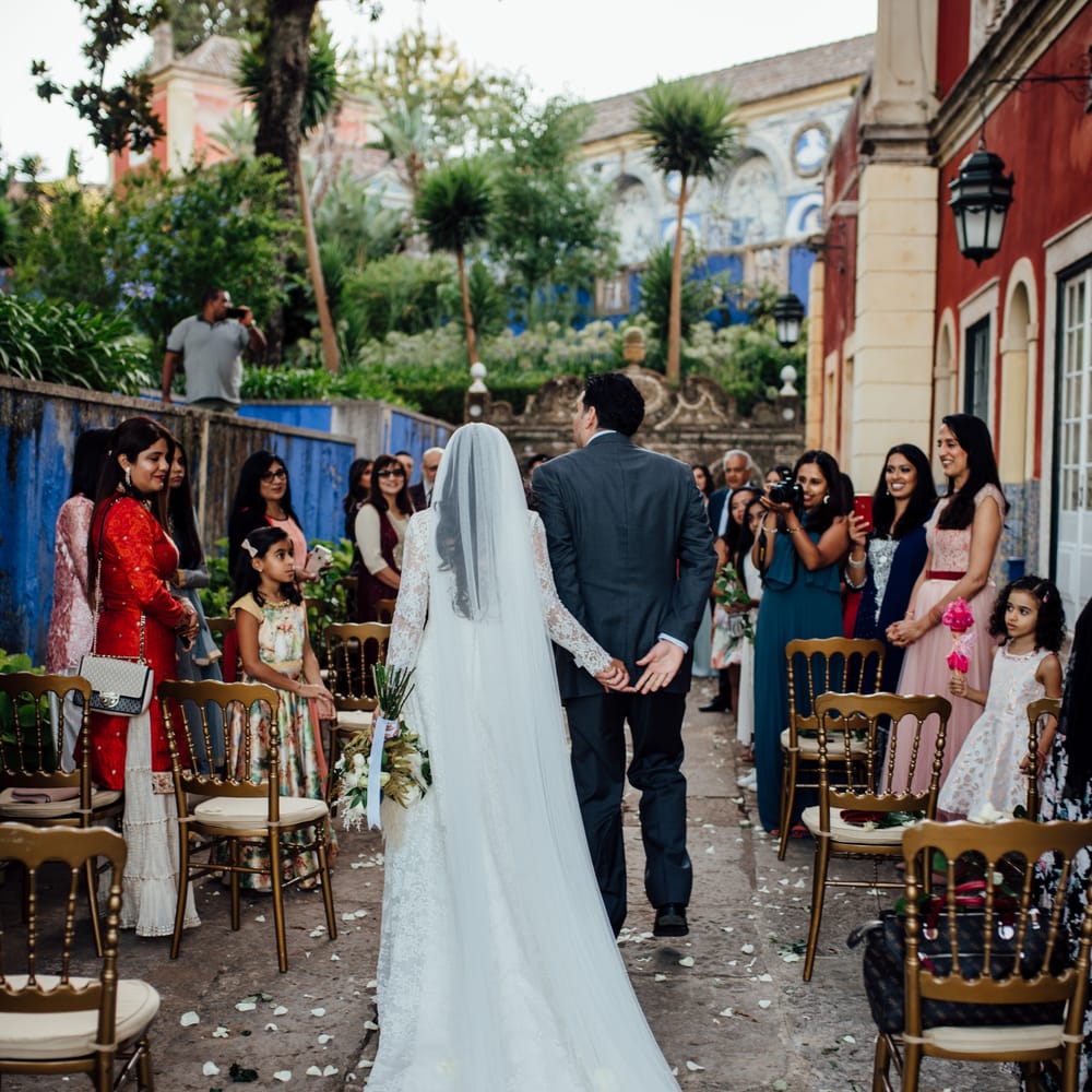 Bride walks down the aisle whilst wearing Pronovias wedding gown and wedding guests look on 