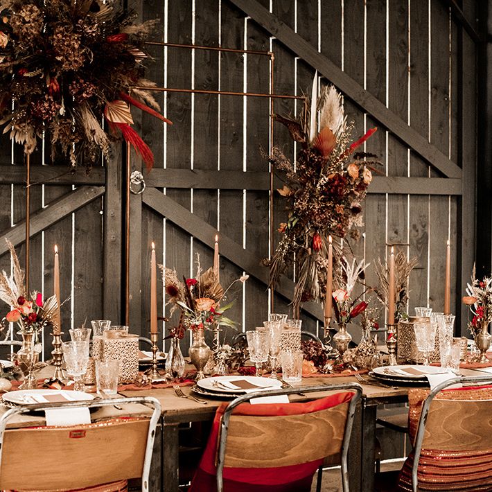 Moroccan inspired table decor at rustic farm wedding with gold lanterns and red and orange wedding flowers 