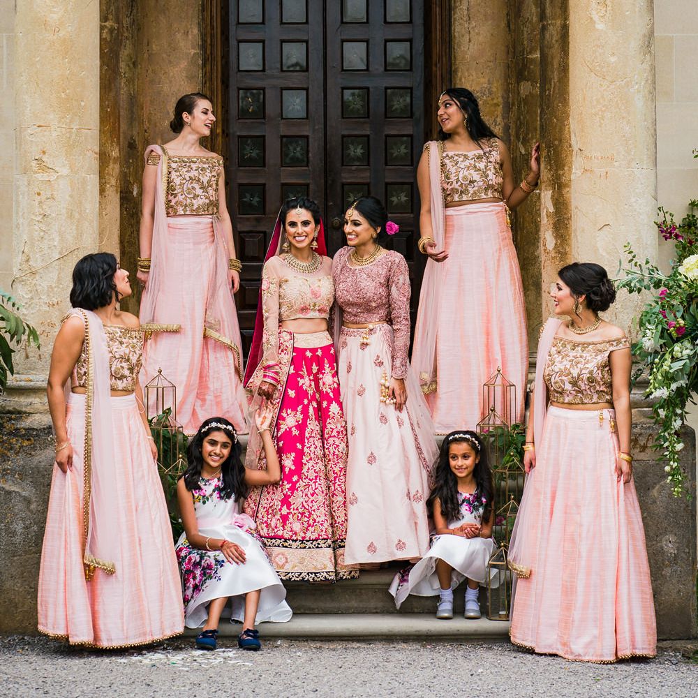 Bridesmaids in pink traditional Asian wedding attire standing on the steps at Elmore Court wedding venue 