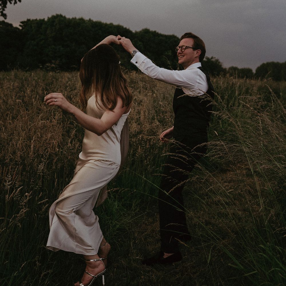 Groom twirls bride around outdoors in the countryside on their wedding day