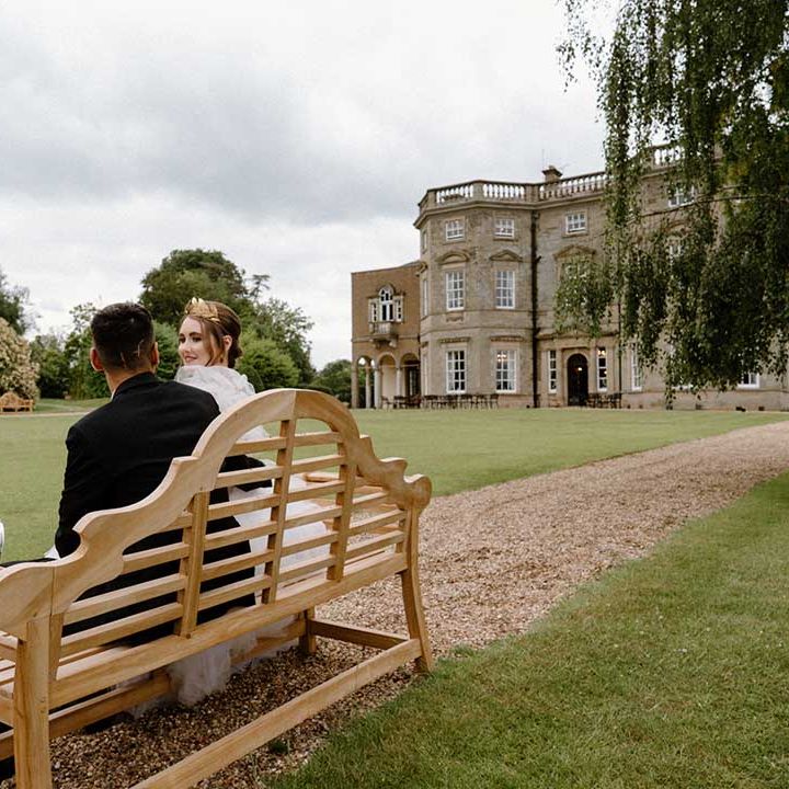 Interabled couple sitting on a bench in the grounds of Bourton Hall wedding venue in Warwickshire 