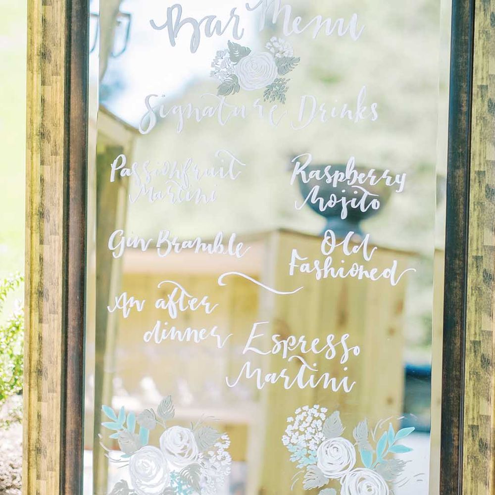 mirror wedding sign with cocktail menu written in white ink 