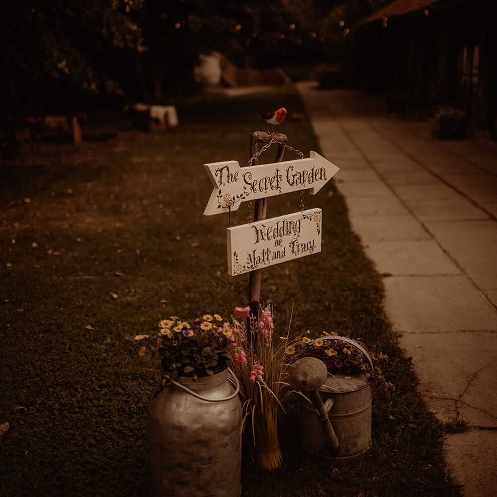 The secret garden wedding sign with tin watering cans filled with flowers 