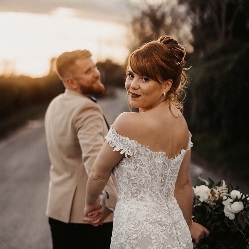 Bride wearing curled updo and lace wedding dress from Maggie Sottero with button details 