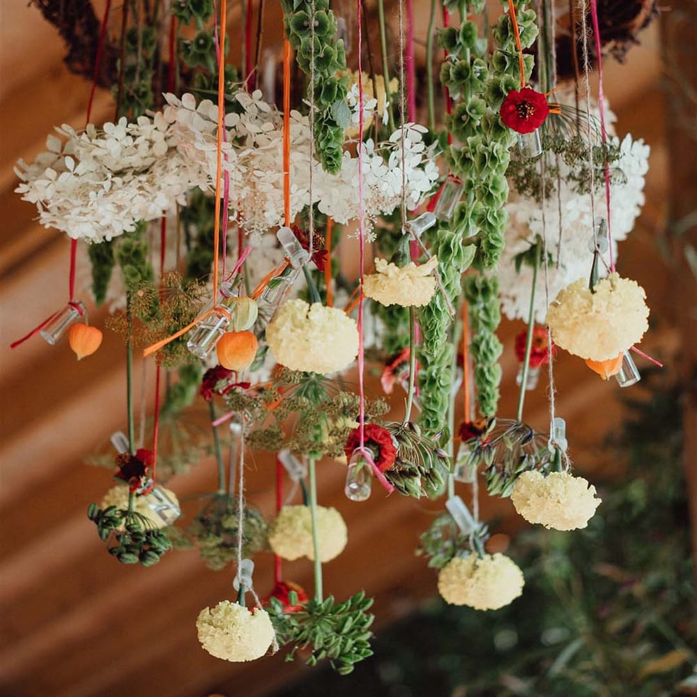 Hanging plant wedding decor from twisted wooden ring with white, yellow and orange flowers including hydrangea 