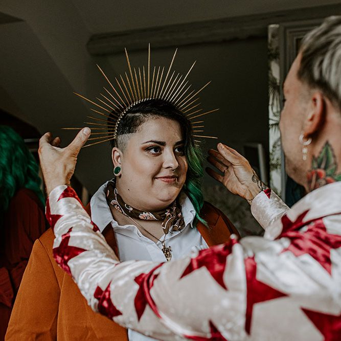 Groom places gold crown on wedding guests head on the morning of his wedding day