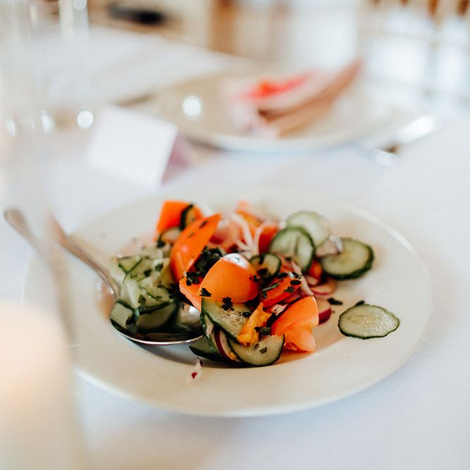 Bowl of salad with ribbons of cucumber and tomato in white plate for reception food