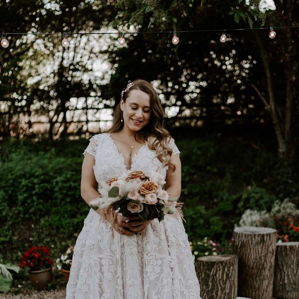 Homemade lace wedding dress with deep v neck and neutral toned bouquet