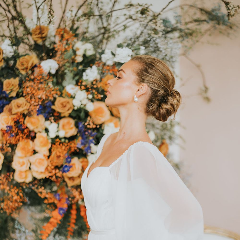 Bride wearing a sheer balloon sleeve wedding dress with her brown hair in a messy updo and natural glowy makeup 