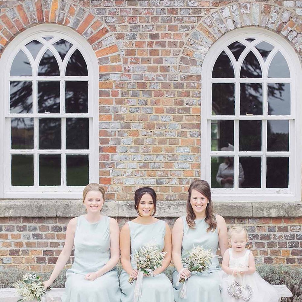 Bridesmaids in baby blue satin bridesmaid dresses with pink ribbons at Wasing Park