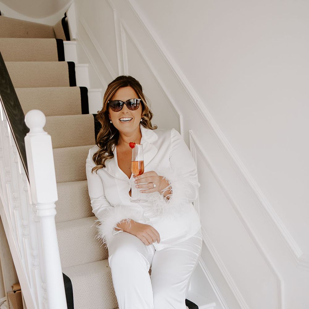 Bride wears sunglasses and white silk pyjamas complete with fluffy cuffs 