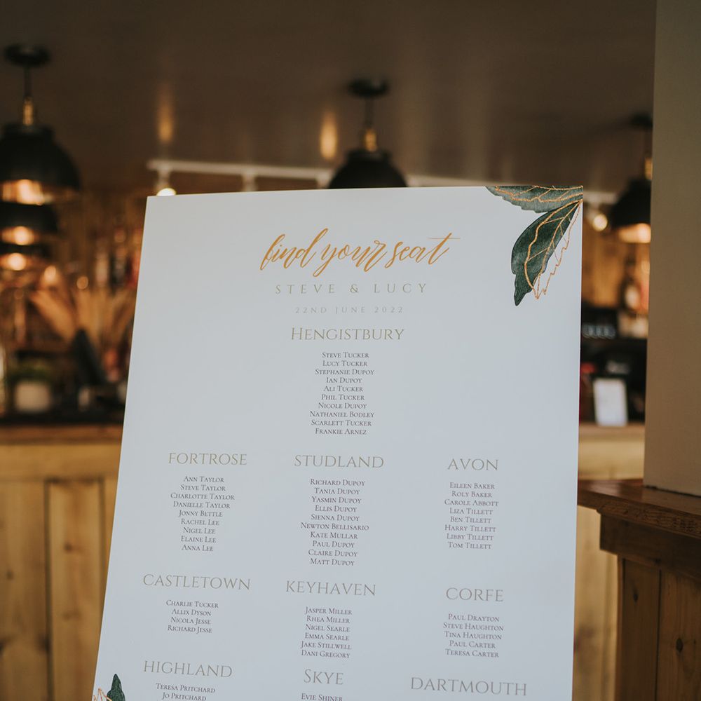 White wedding signage with leaf illustration on wooden easel 