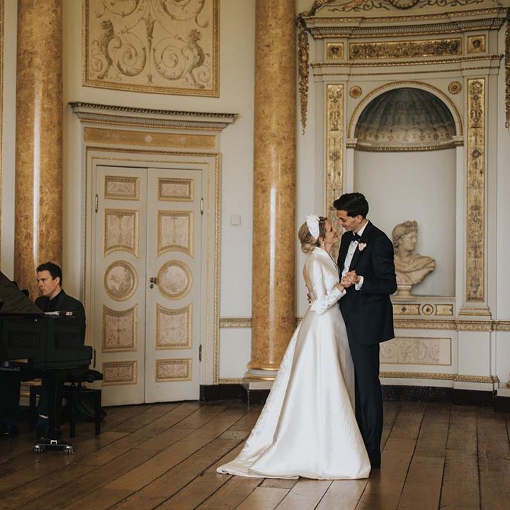The bride and groom share an intimate dance as a pianist plays for their Bridgerton inspired wedding day 