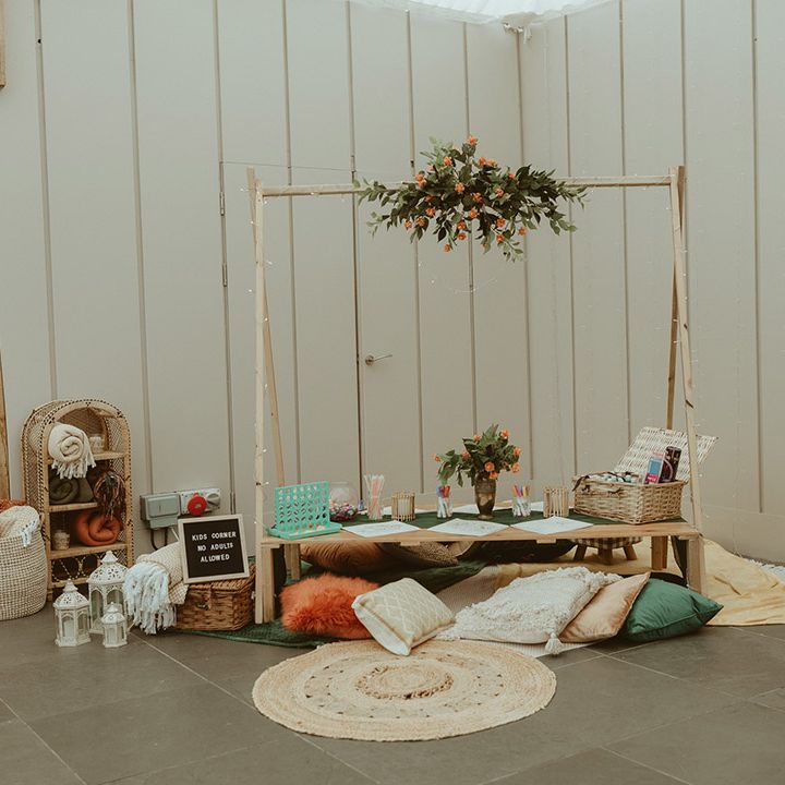 Kid's station with blankets, colouring, pretzel bar next to the three tier orange and white iced wedding cake autumn wedding