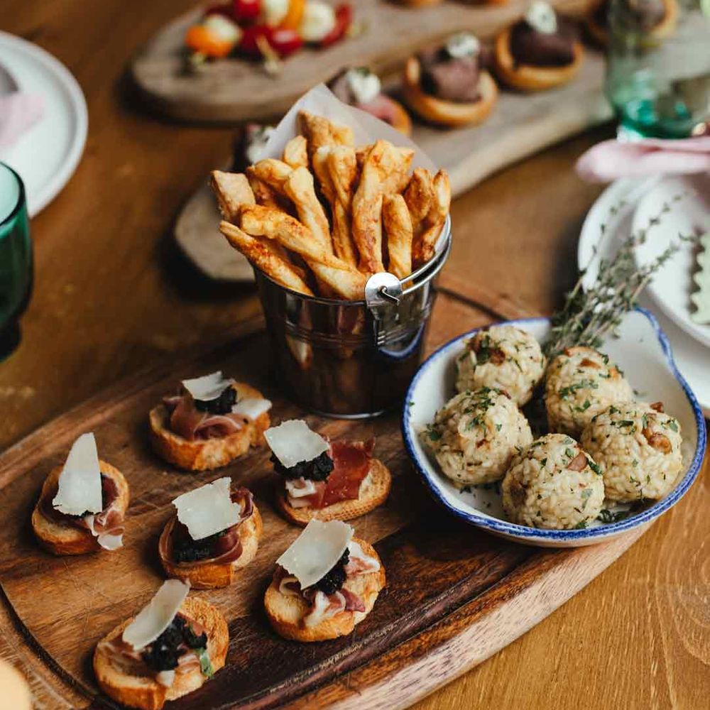 A variety of wedding food canapés on rustic wooden slates - food section of wedding budget spreadsheet